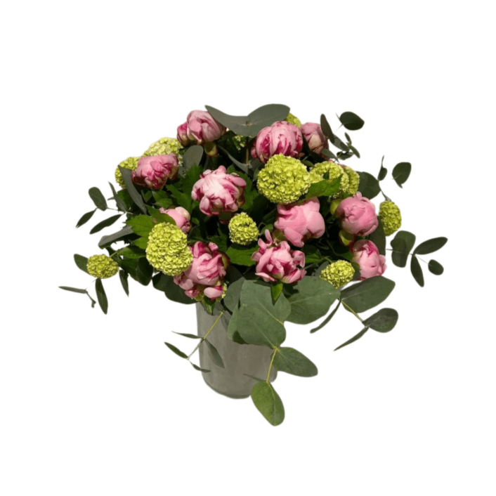 Der Blumenstrauß „Pfingstzauber“ von florali besteht aus grünem Laub, Eukalyptus, hellgrünen hortensienartigen Blüten und rosa Pfingstrosen, rund arrangiert in einer klaren Vase vor weißem Hintergrund.