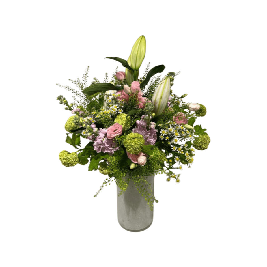 Eine hohe Glasvase gefüllt mit einem frischen Blumenstrauß von LelliLilie aus rosa Lilien, grünen Hortensien, weißen Gänseblümchen und verschiedenen Grünpflanzen, kunstvoll arrangiert vor einem weißen Hintergrund.